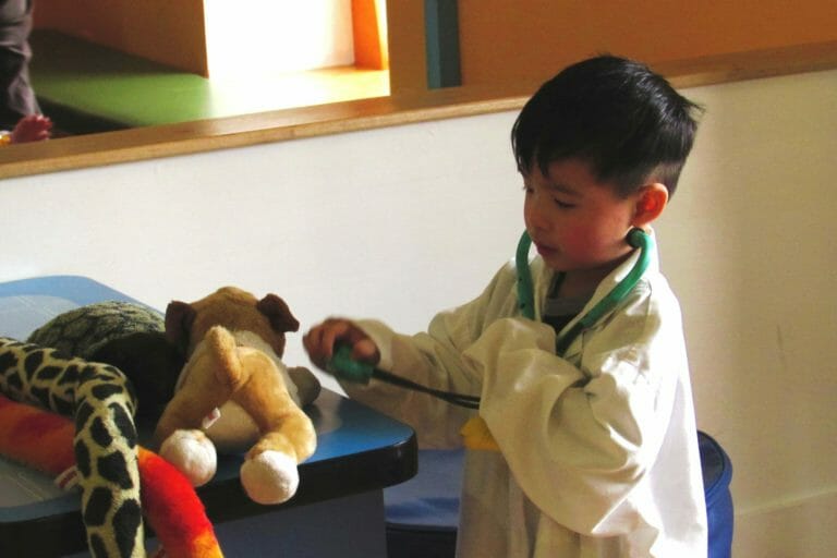 child wearing white doctors coat in vet's office.
