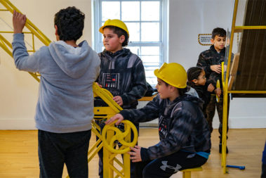 Children with hardhats on their head playing in our House About It exhibit.