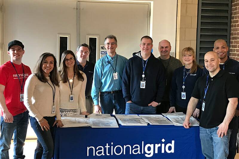 National Grid employees smiling in front of a National Grid table.