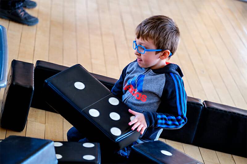 Child playing with dominoes in our Big Games exhibit.