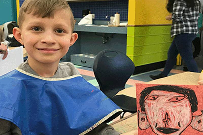 Child smiling with arts and craft creation.