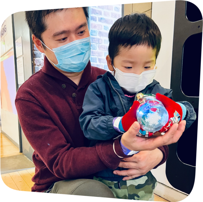 father holding child who is holding a snow globe