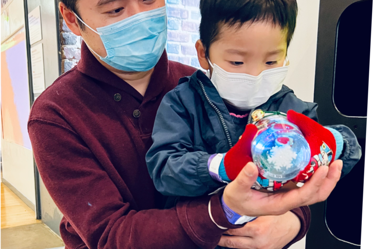 father holding child who is holding a snow globe