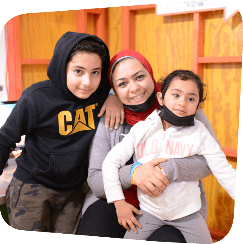 smiling boy behind smiling mom holding wriggly child