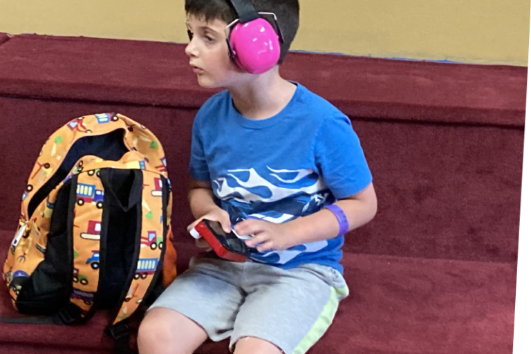 a child with pink headphones from the sensory toolkit on his head looking into the middle distance
