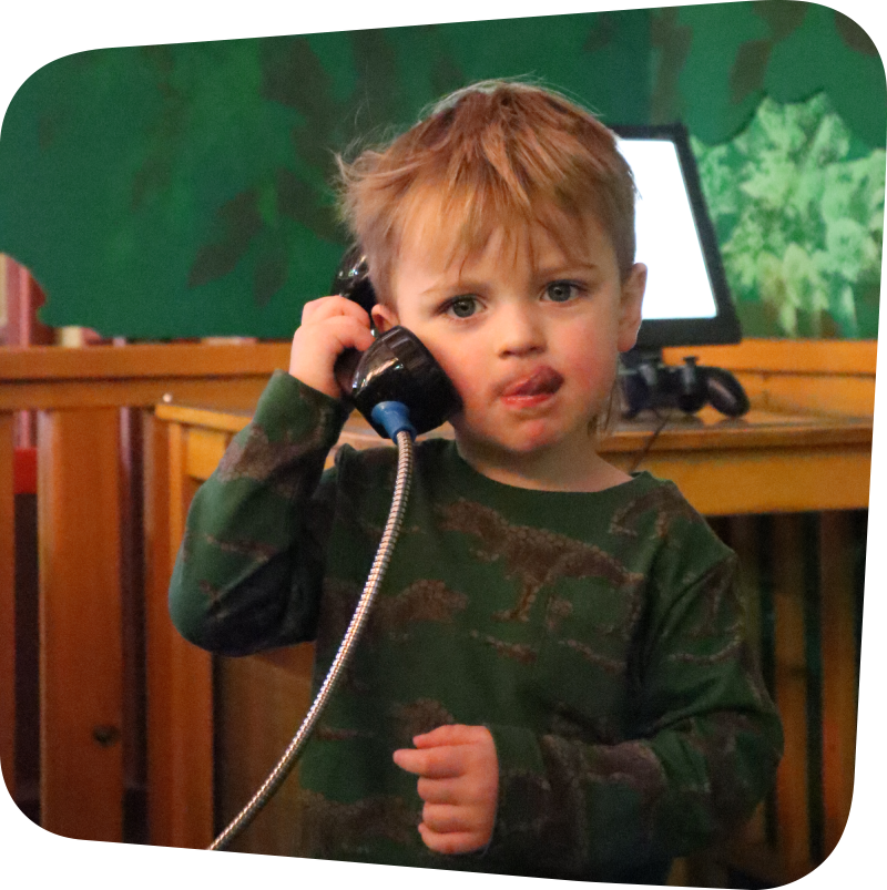 Child featured on a phonebooth style phone while sticking their tongue out to the side