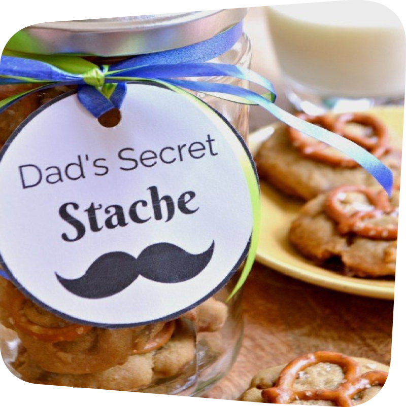 A mason jar filled with snack good and a tag on it saying Dad's Secret Stache with black mustache below