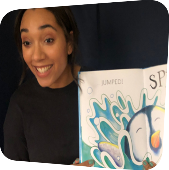 A woman smiling and displaying a story book. The open book shows an illustrated penguin jumping into water with a splash.