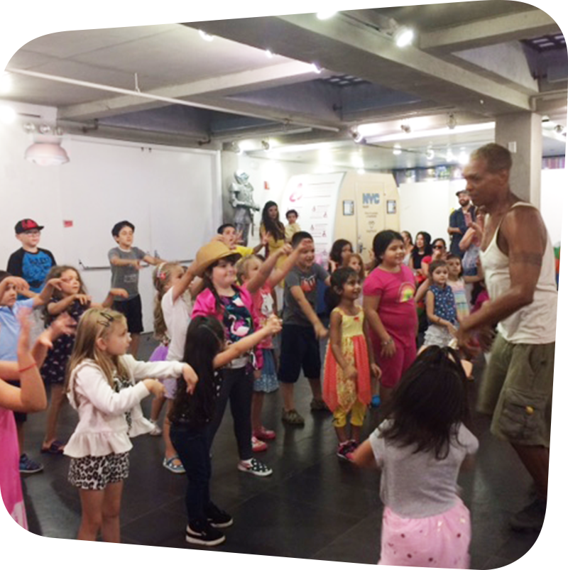 Several children surrounding Walter Rutledge while he teaches them dance moves