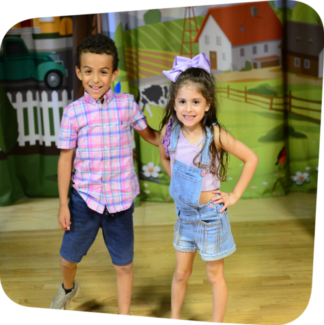 two children smiling standing on the stage in the Portia's Playhouse exhibit