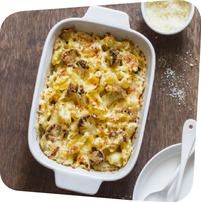 Cooked pan of cauliflower mac n cheese on a brown wooden table.