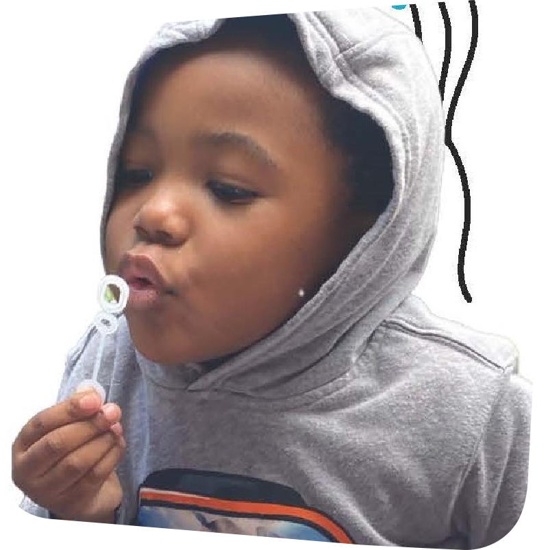 child in a grey hoodie blowing bubbles