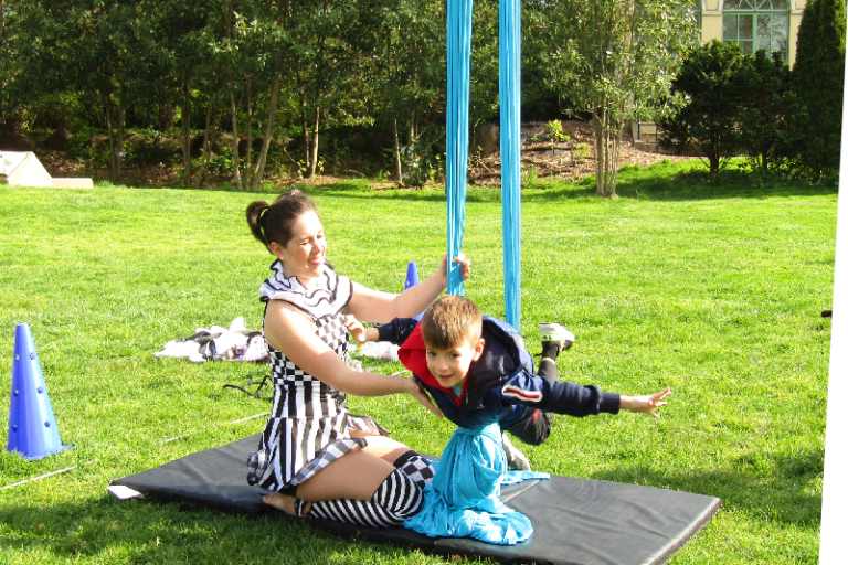 acrobat helping child visitor balance in her rig