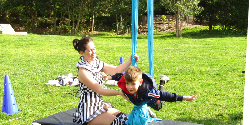acrobat helping child visitor balance in her rig