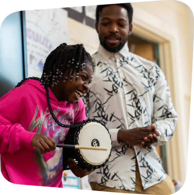 Instructor watching a girl play a drum