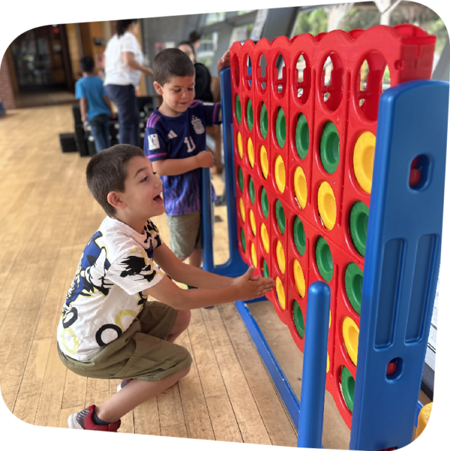 Two happy boys joyfully playing with the Connect Four components in the big play room.