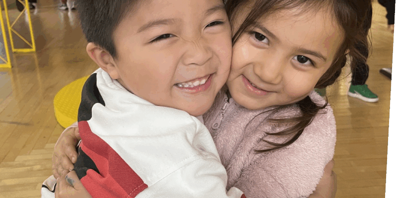 Dec press release Two kids hugging in House About It