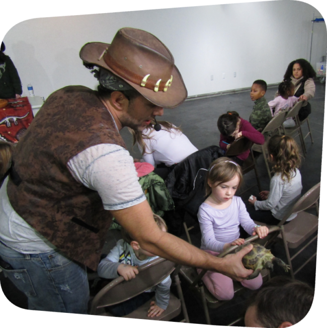 Binx holding a turtle in front of a little girl in the gallery