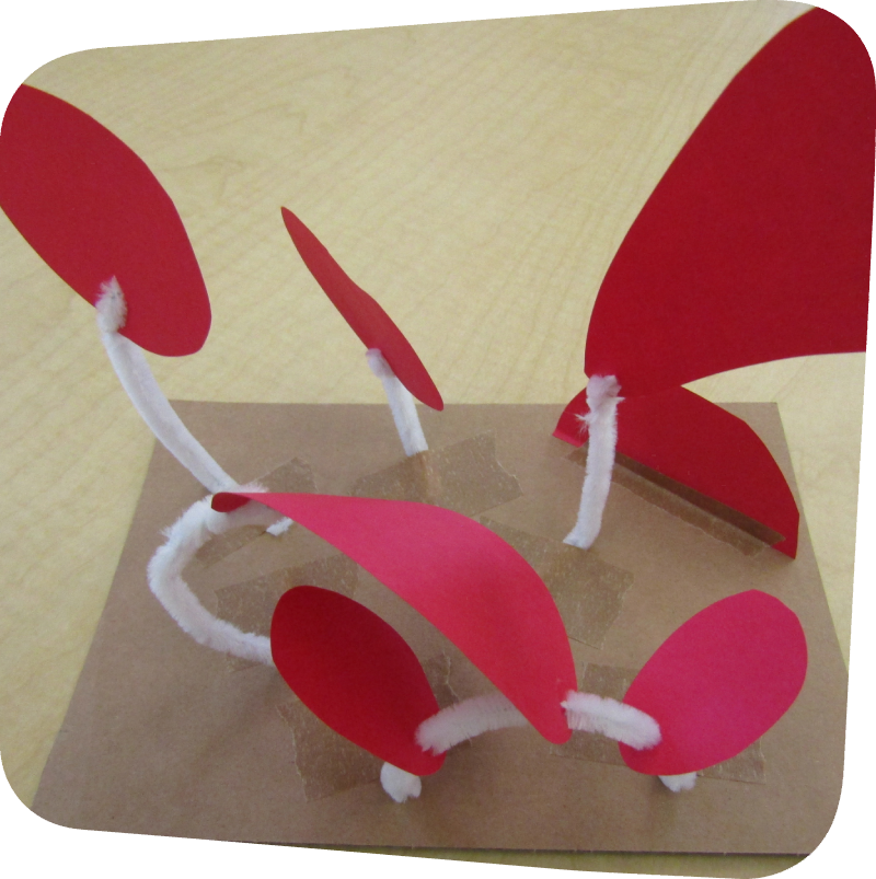 paper shapes connected by pipe cleaners on cardboard