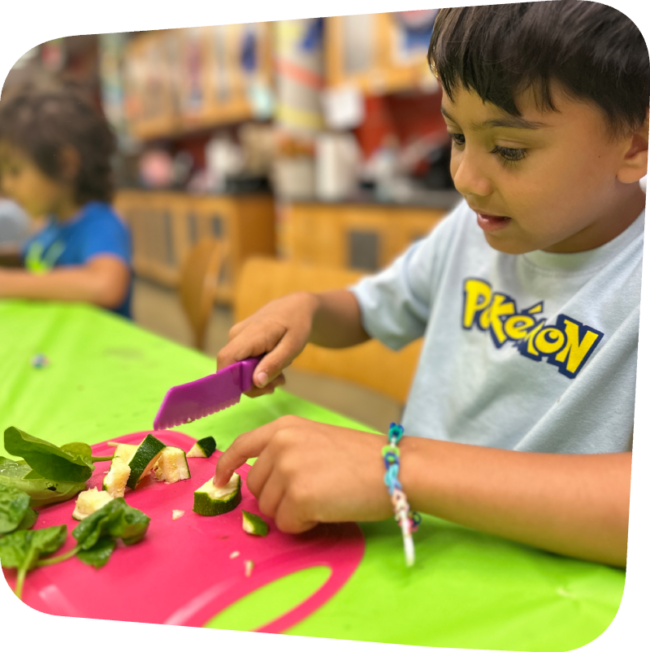 boy chopping veggies in classroom