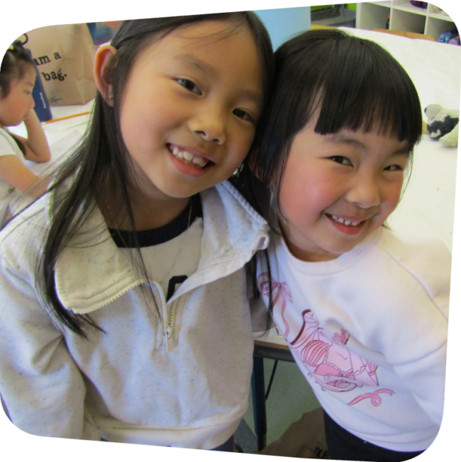 two girls smiling and hugging in the art classroom at the Staten Island Children's Museum