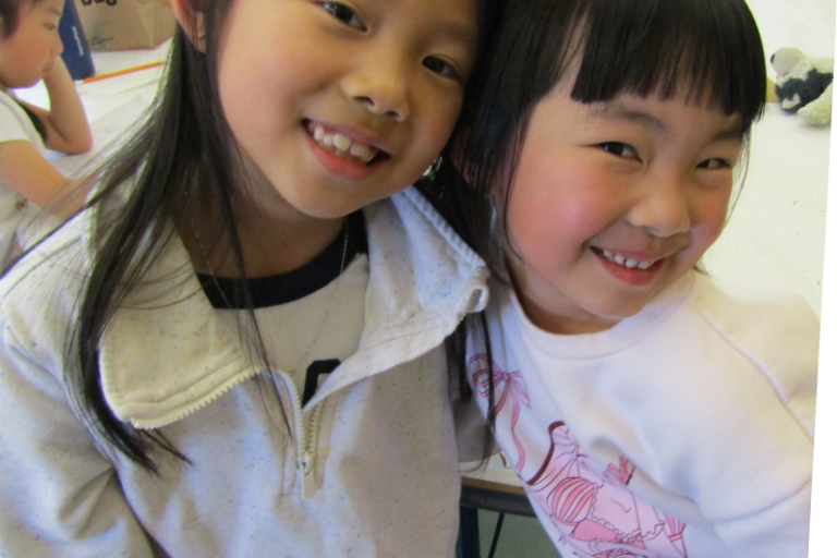 two girls smiling and hugging in the art classroom at the Staten Island Children's Museum
