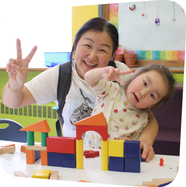 adult with child in her lap with toys on table