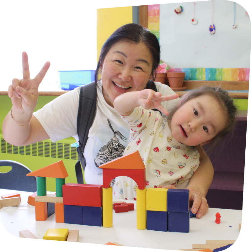 adult with child in her lap with toys on table