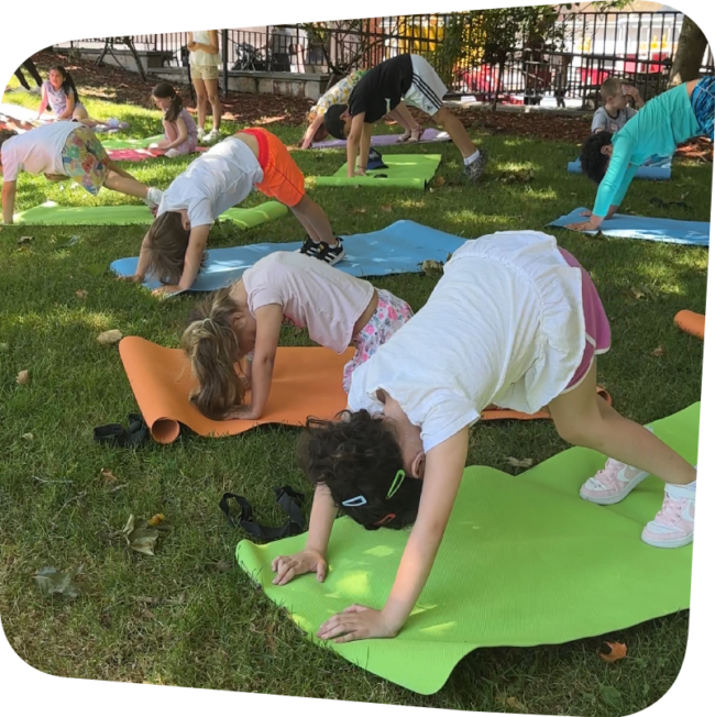 kids in a yoga pose outside in the meadow at the Staten Island Children's Museum on a sunny day