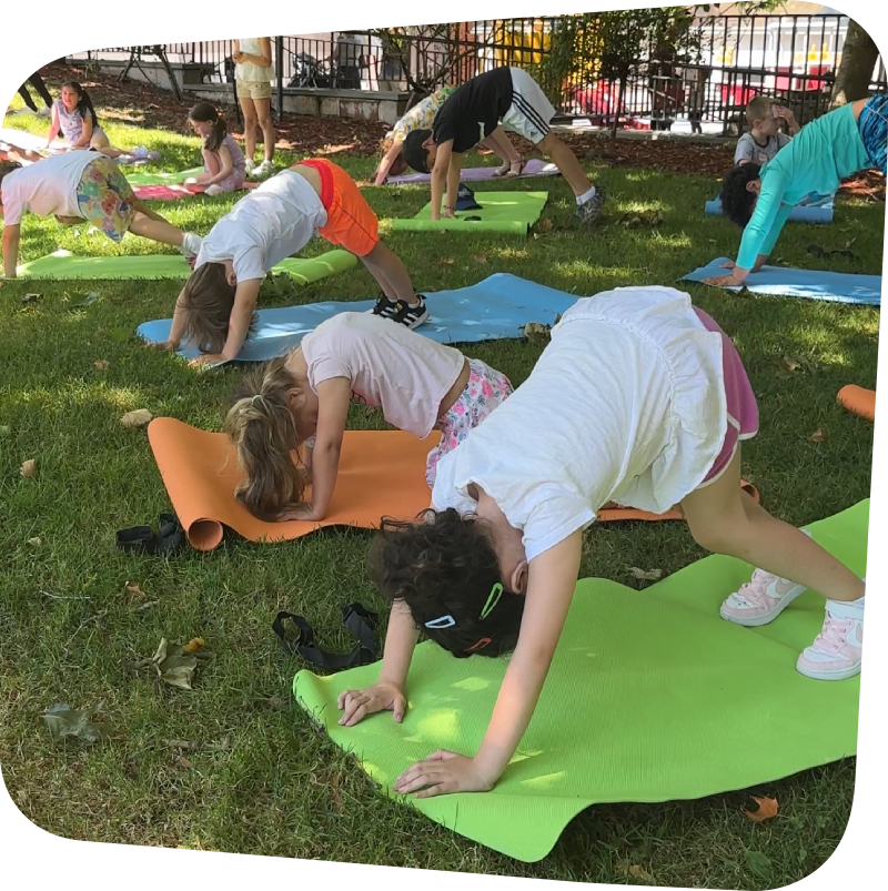 kids in a yoga pose outside in the meadow at the Staten Island Children's Museum on a sunny day