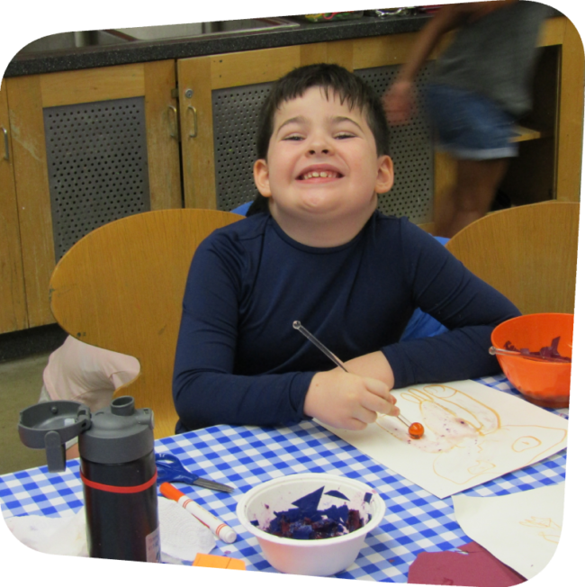 smiling boy doing a science project with seeds in art classroom at the State Island Children's Museum