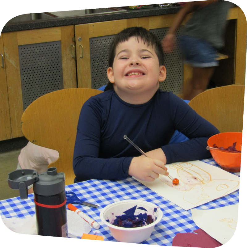 smiling boy doing a science project with seeds in art classroom at the State Island Children's Museum