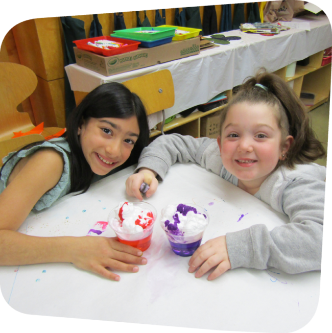 two smiling girls with their clouds in a cup science project in the art room at the Staten Island Children's Museum