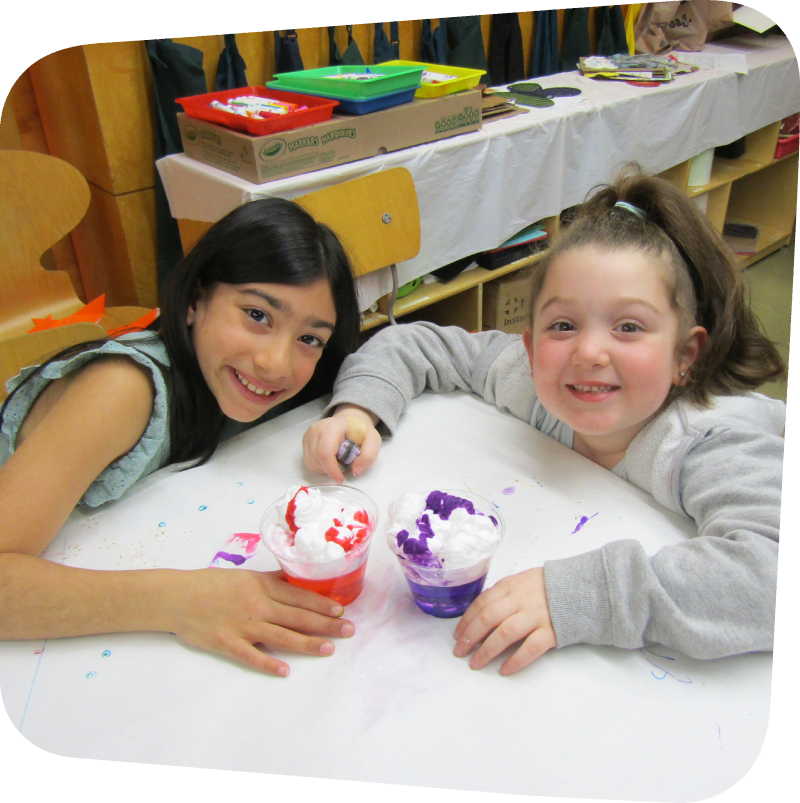 two smiling girls with their clouds in a cup science project in the art room at the Staten Island Children's Museum
