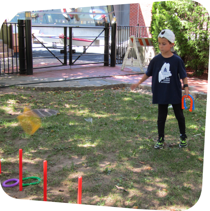 little boy tossing horseshoes at a target in the meadow at the Staten Island Children's Museum