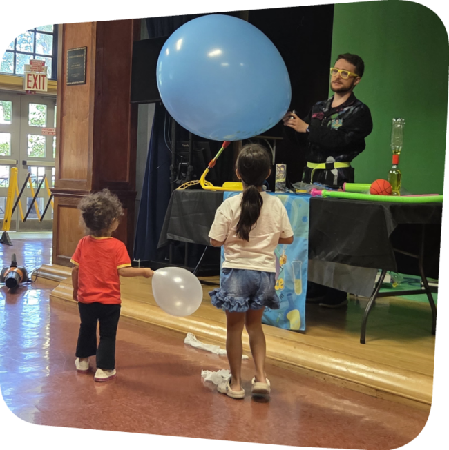 crazy scientist blowing up a balloon in front of two children at the Staten island Children's Museum