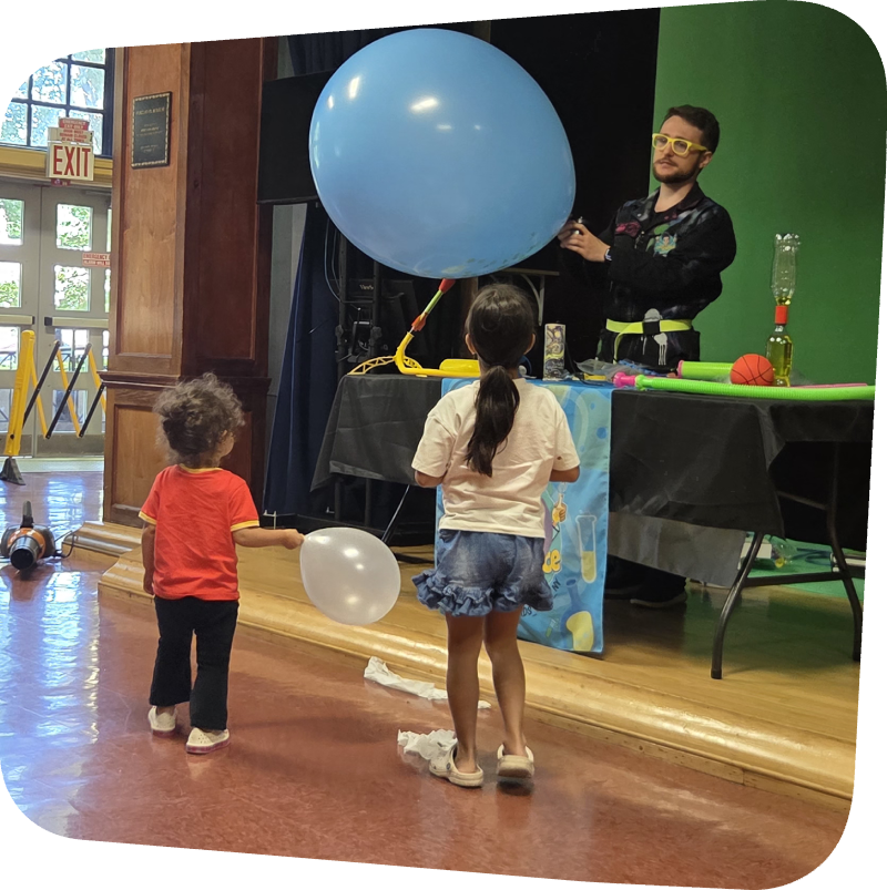 crazy scientist blowing up a balloon in front of two children at the Staten island Children's Museum