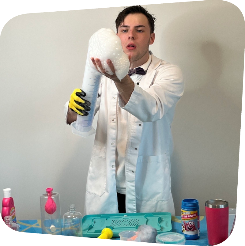 scientist holding a beeker overflowing with bubbles in front of a work table