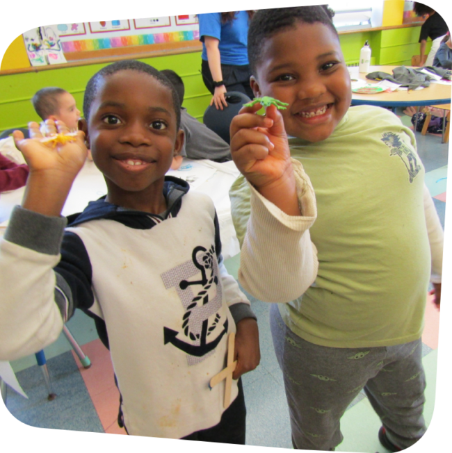 two smiling boys dispalying plastic bugs in art class