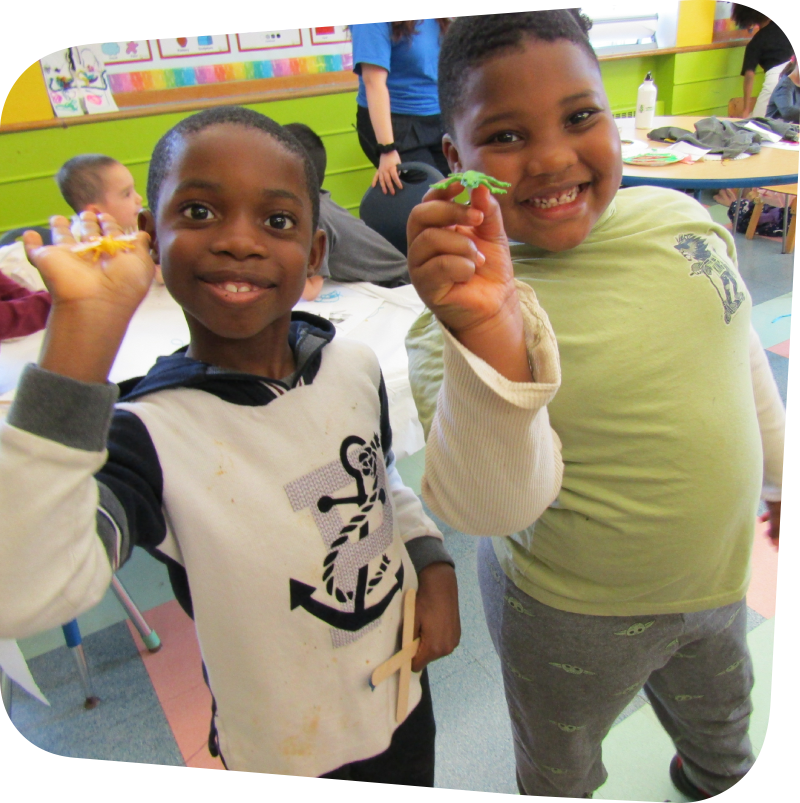 two smiling boys dispalying plastic bugs in art class