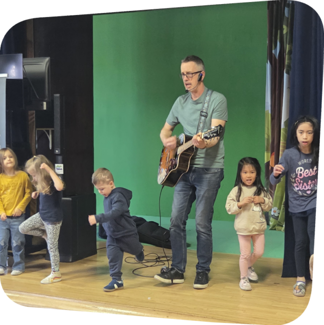 kids dancing on stage at the Staten Island Children's Museum to Mr. Patrick who is playing a guitar