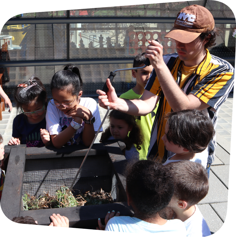 kids watching an compost instructor turn a crank in a compost bin in the Garden terrace at the Staten Island Children's Museum
