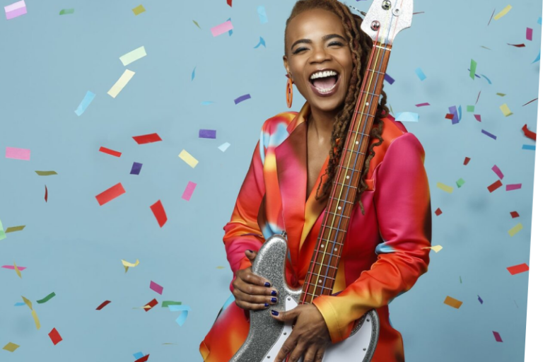 Divi Roxx Kids holding a bass guitar with confetti falling around her
