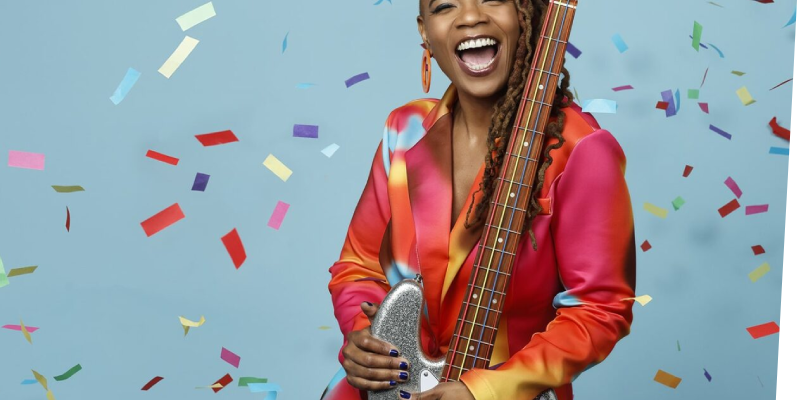 Divi Roxx Kids holding a bass guitar with confetti falling around her