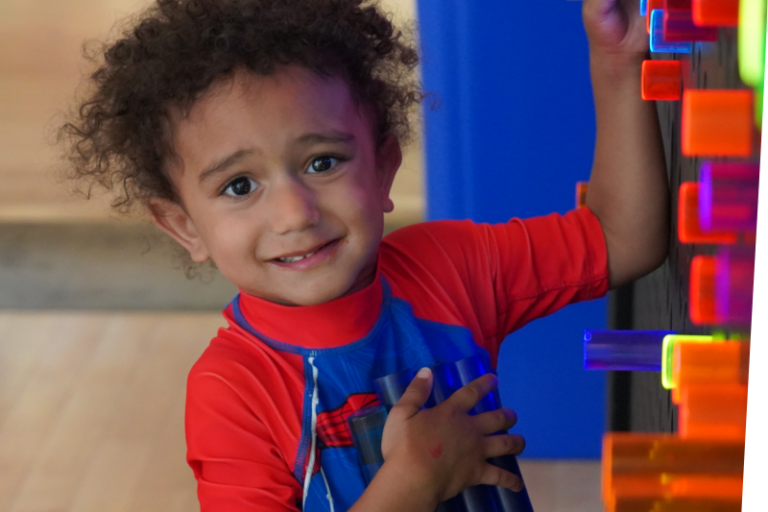 smiling boy playing at the light bright in big games t the Staten Island Children's Museum