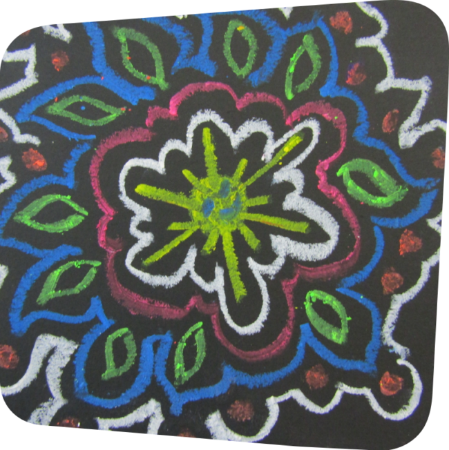 mola design of green, blue, red and white on a black piece of paper