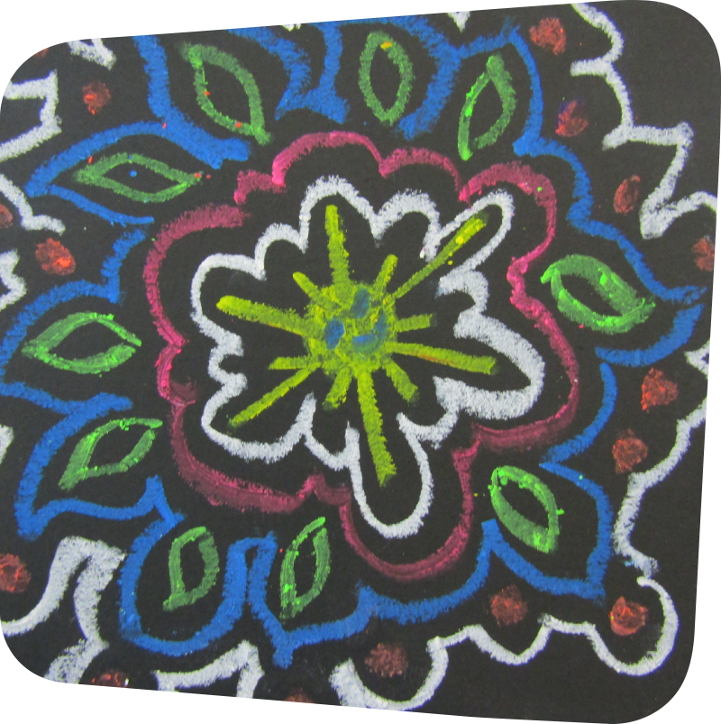 mola design of green, blue, red and white on a black piece of paper