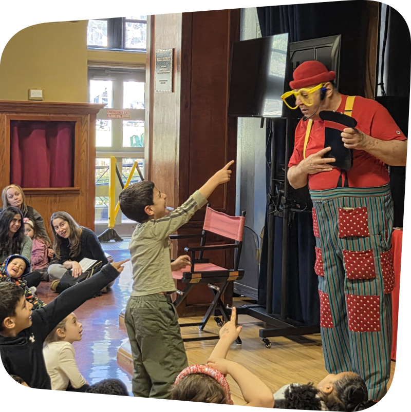 Silly billy performing on stage at the Staten Island Children's Museum with kids watching and laughing