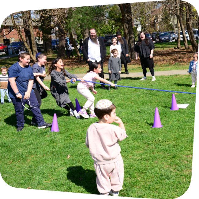 smiling kids engaging in tug of war on the lawn at the Staten Island Children's Museum