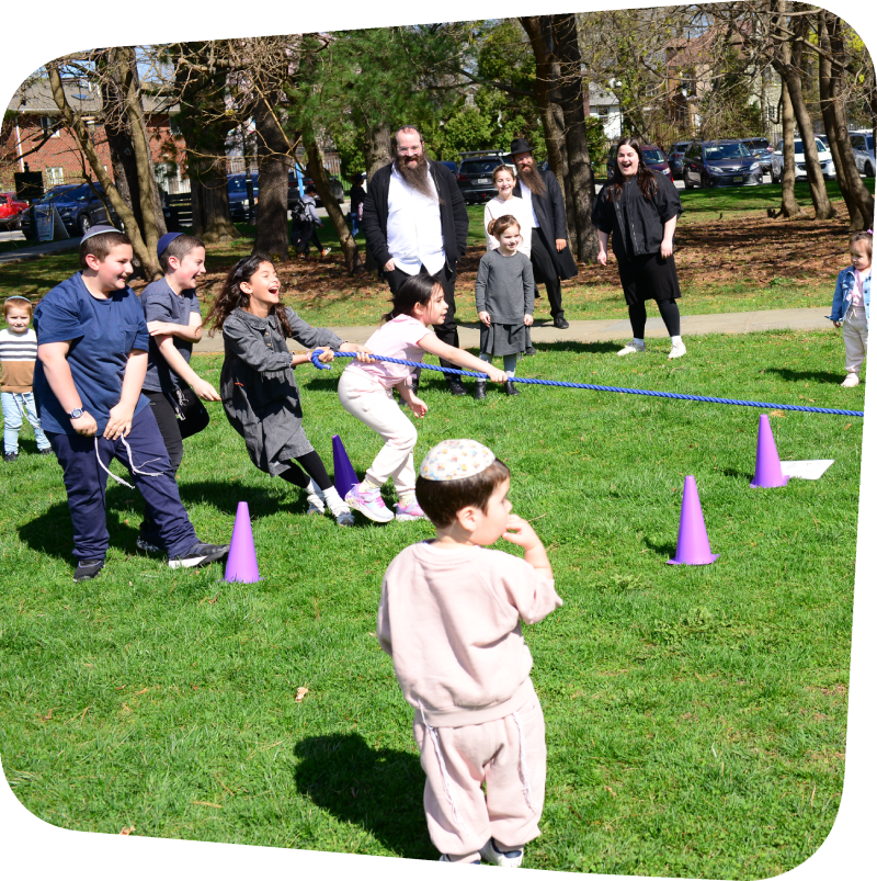 smiling kids engaging in tug of war on the lawn at the Staten Island Children's Museum